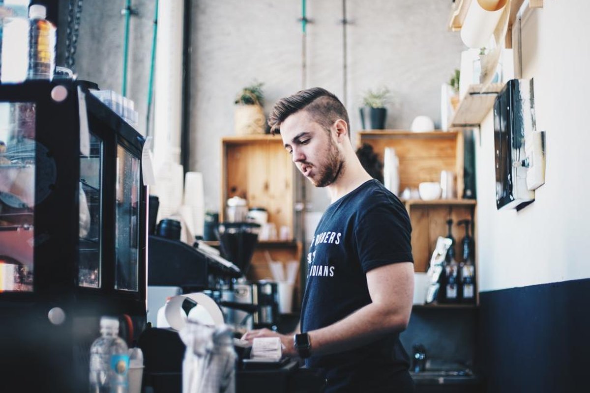 Cafe owner working behind the counter of his small coffee shop